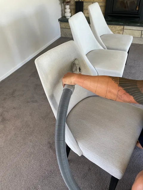 Hand extraction tool cleaning a light upholstered armchair