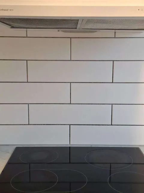 After cleaning: the same hob and white tiled splashback with fewer visible marks