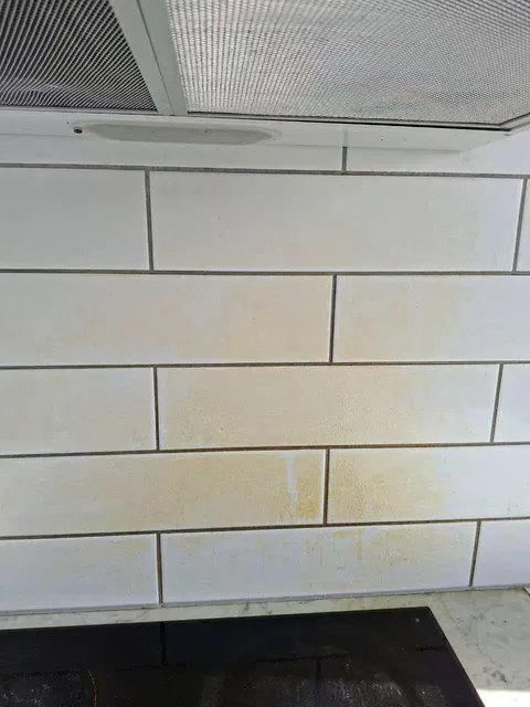 Before cleaning: marks on white splashback tiles and the underside of a rangehood above the hob